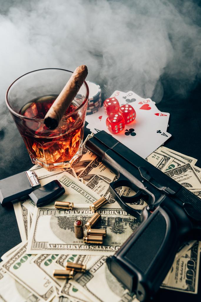 Pistola y balas en la mesa del casino con dinero y objetos de juego
 - Foto, imagen