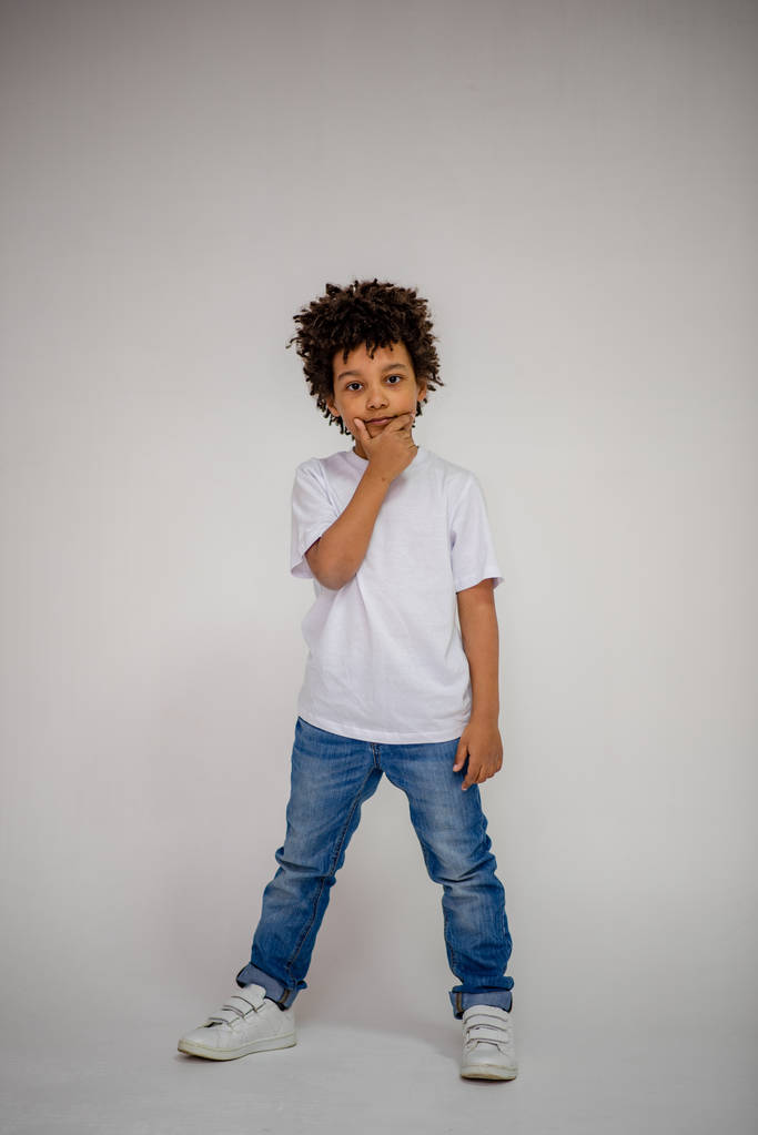ciemnoskóry chłopiec w dżinsach i w biały sweter w różnych pozach pokazuje różne emocje na różnym tle - Zdjęcie, obraz