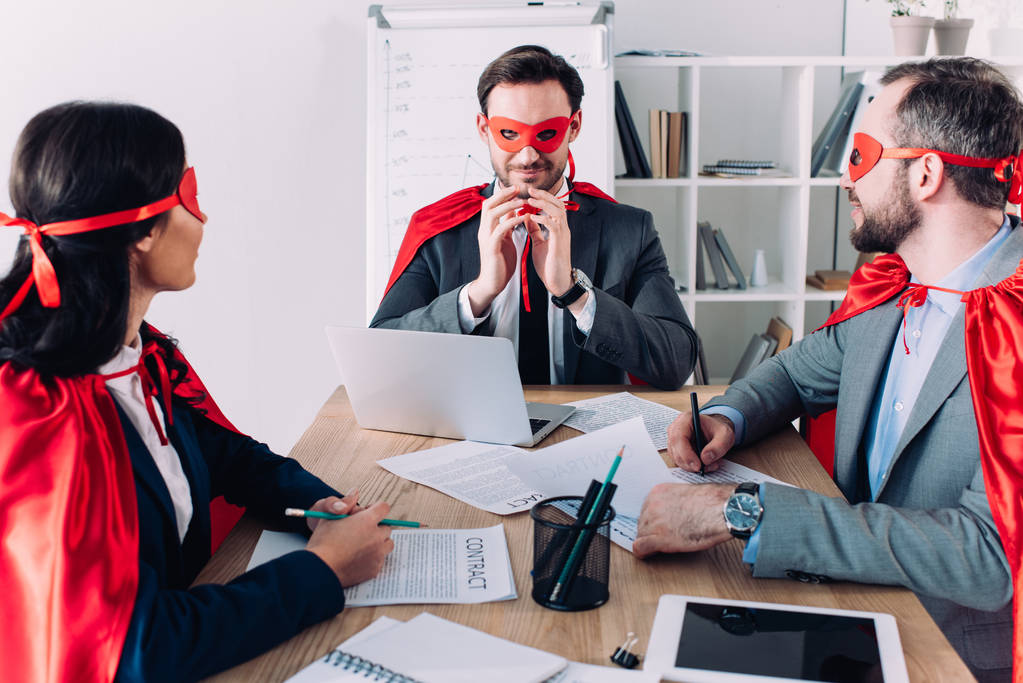 Super podnikatelé v maskách a pláštěnky na schůzce v kanceláři - Fotografie, Obrázek