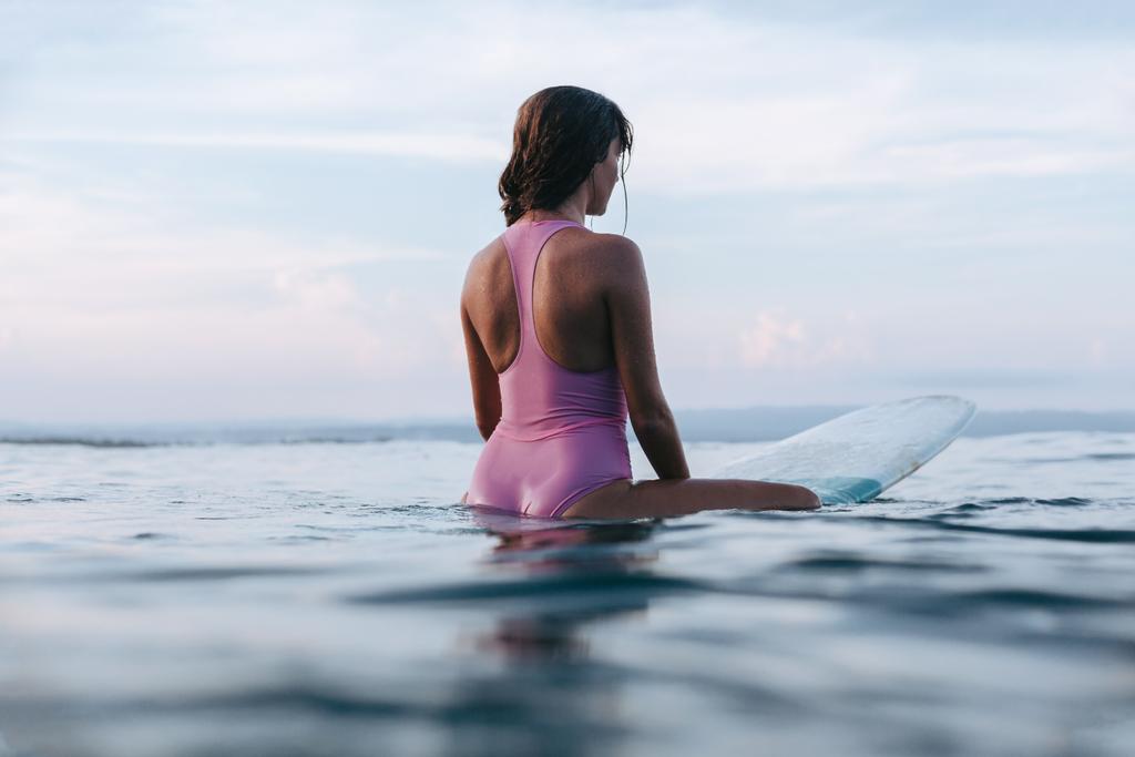 a fiatal sportoló ül a vízben szörfdeszka hátulnézet   - Fotó, kép