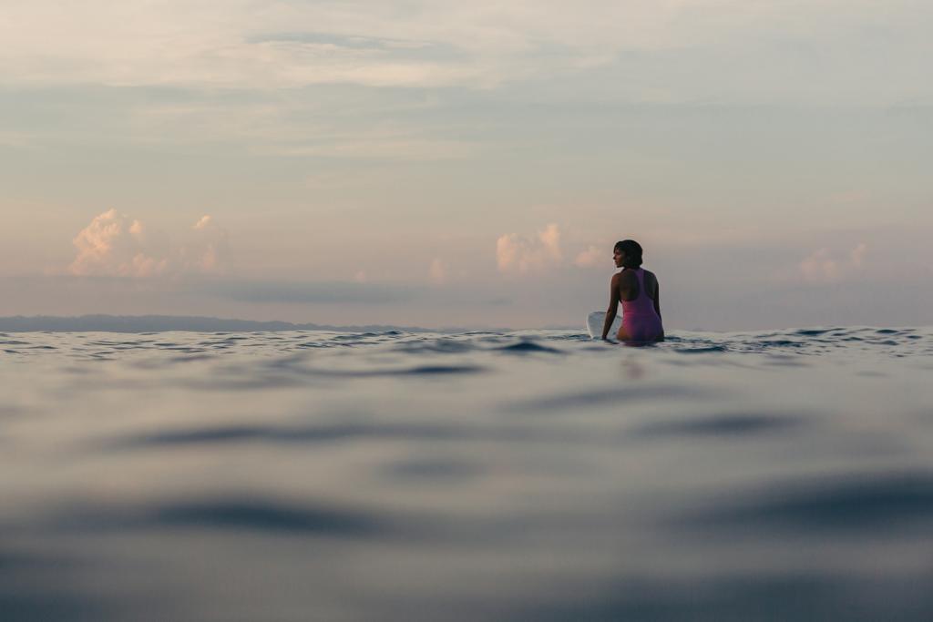 silhouette de surfeur assis sur une planche de surf dans l'eau au coucher du soleil
 - Photo, image