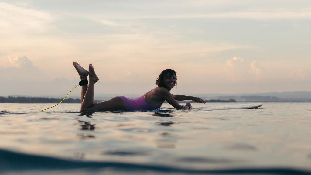 silhueta de mulher deitada na prancha de surf na água no oceano ao pôr do sol
 - Foto, Imagem