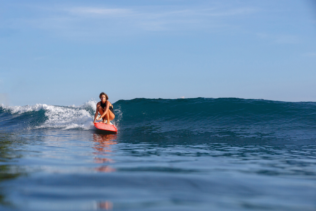 joven surfista hembra cabalgando ola en tabla de surf
   - Foto, Imagen