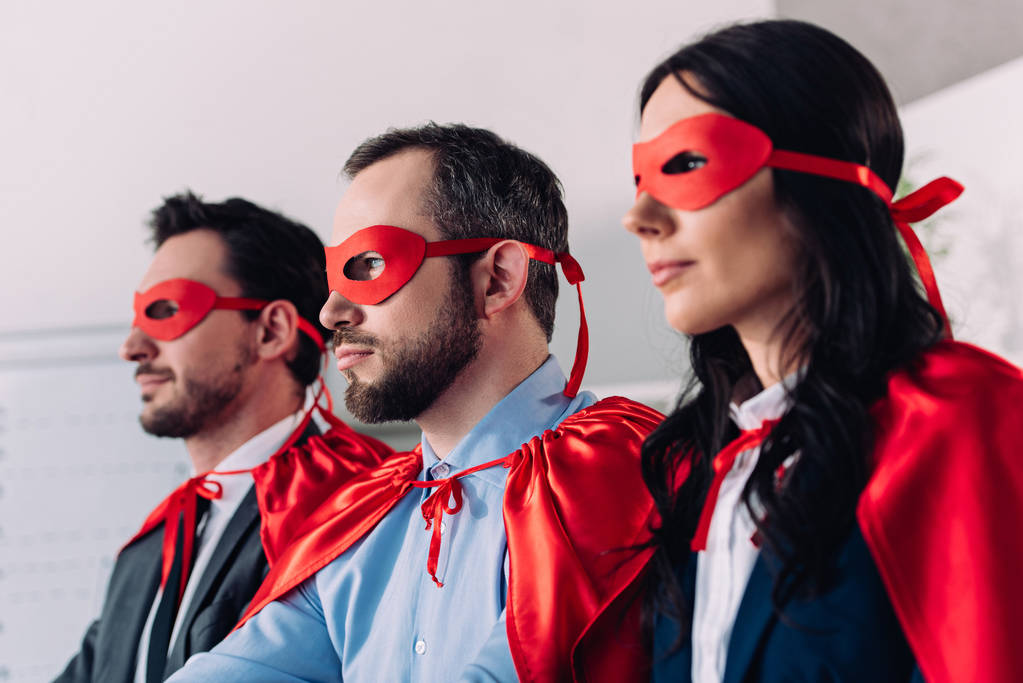 side view of super businesspeople in masks and capes looking away in office - Photo, Image