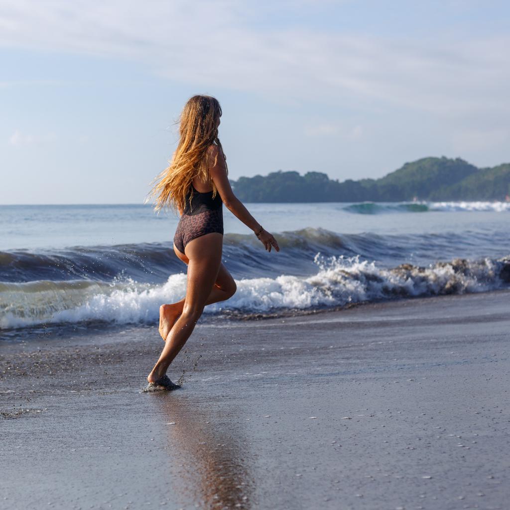 海の近くの熱帯のビーチを走る若い女性 - 写真・画像