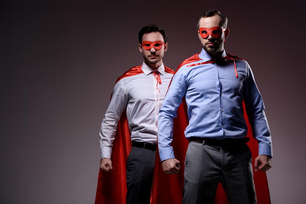 handsome super businessmen in masks and capes standing with fists isolated on grey - Photo, Image