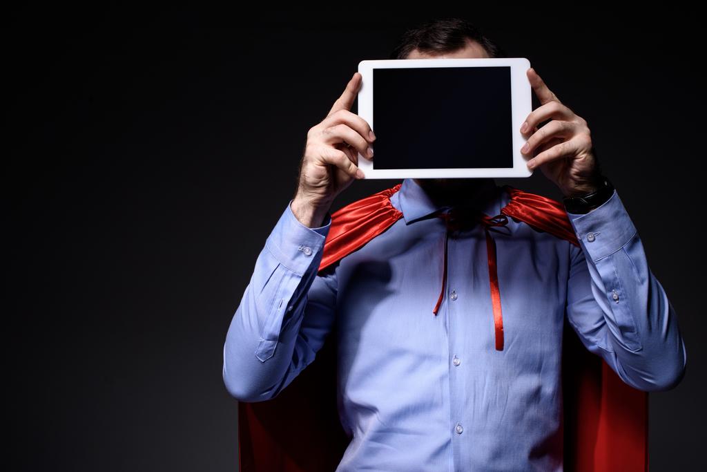 super hombre de negocios en la capa que cubre la cara con la tableta aislada en negro
 - Foto, Imagen