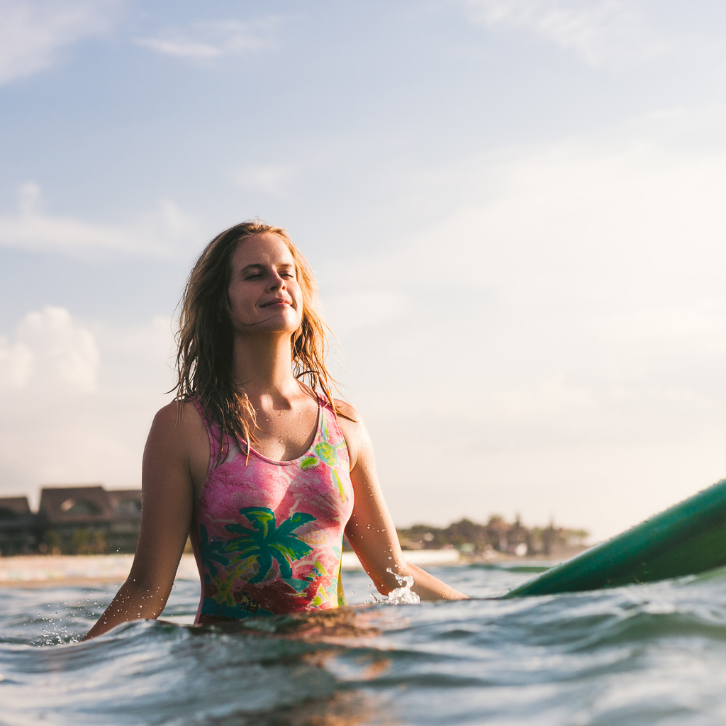 retrato de jovem mulher em roupa de banho descansando sobre prancha de surf no oceano
 - Foto, Imagem