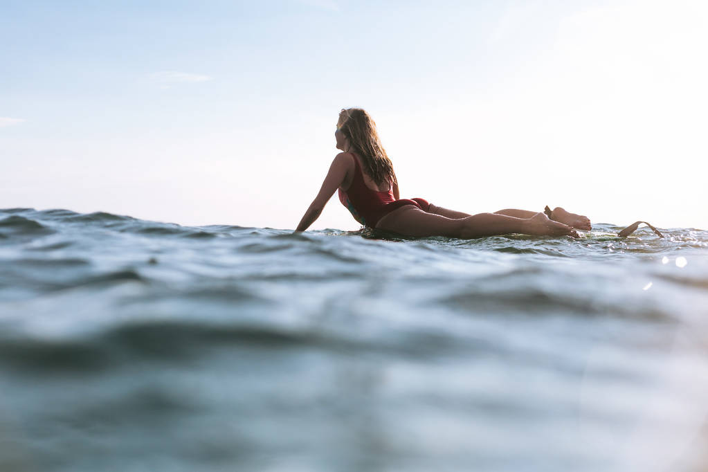 γυναίκα στο κολύμπι κοστούμι που βρίσκονται επί του σκάφους σερφ στον ωκεανό ηλιόλουστη ημέρα - Φωτογραφία, εικόνα