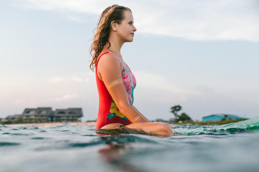 Seitenansicht einer nachdenklichen jungen Frau, die auf einem Surfbrett im Ozean ruht - Foto, Bild