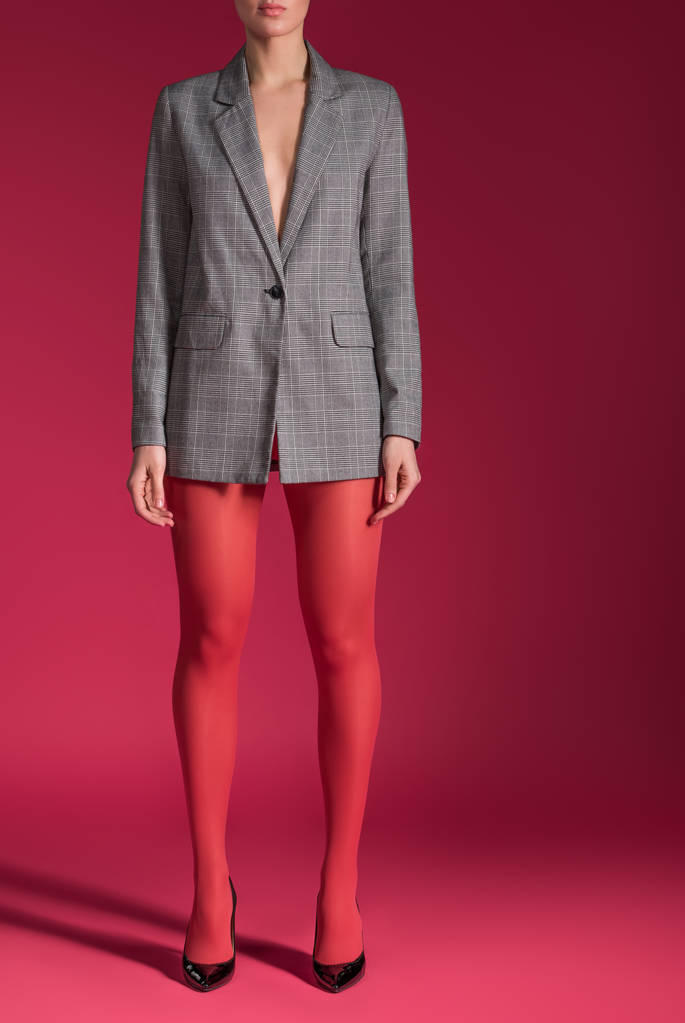 Cropped view of woman wearing red tights and grey jacket on red background - Photo, Image