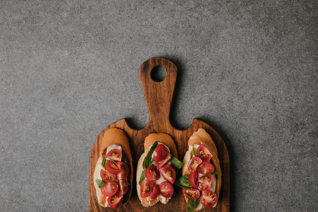 vista superior de la bruschetta italiana gourmet sobre tabla de cortar de madera en gris
   - Foto, imagen