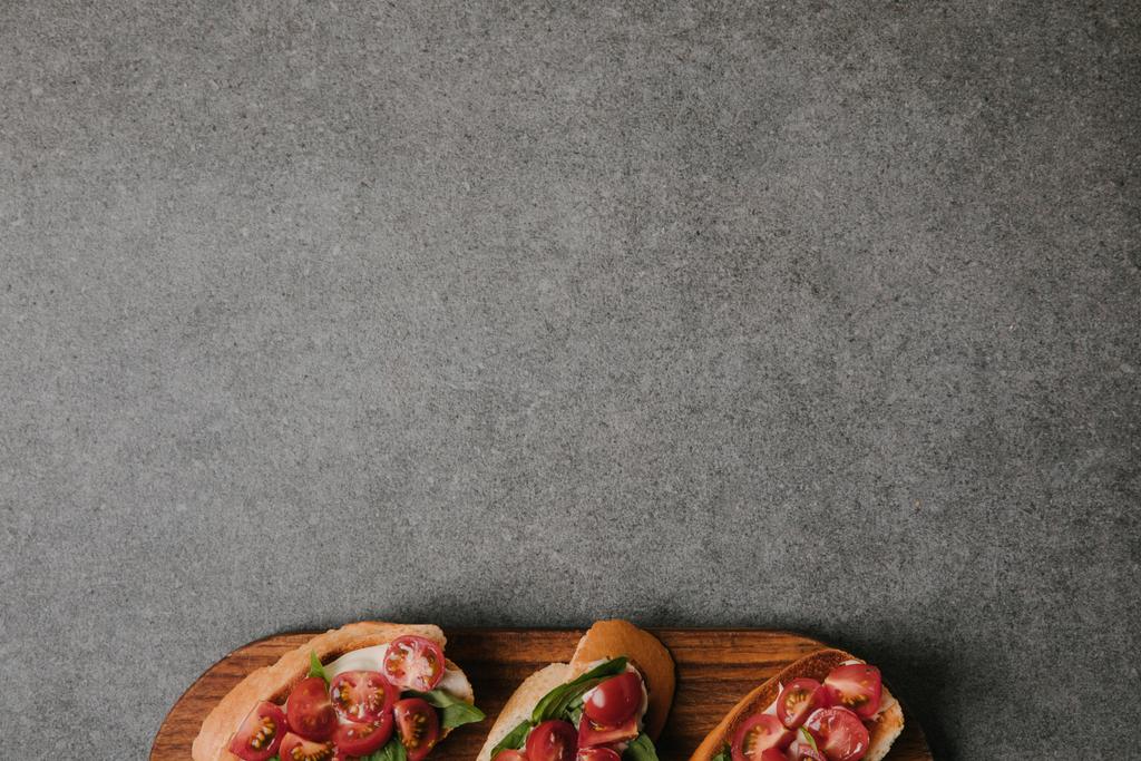 vista dall'alto di deliziose bruschette italiane su tavola di legno su fondo grigio
 - Foto, immagini