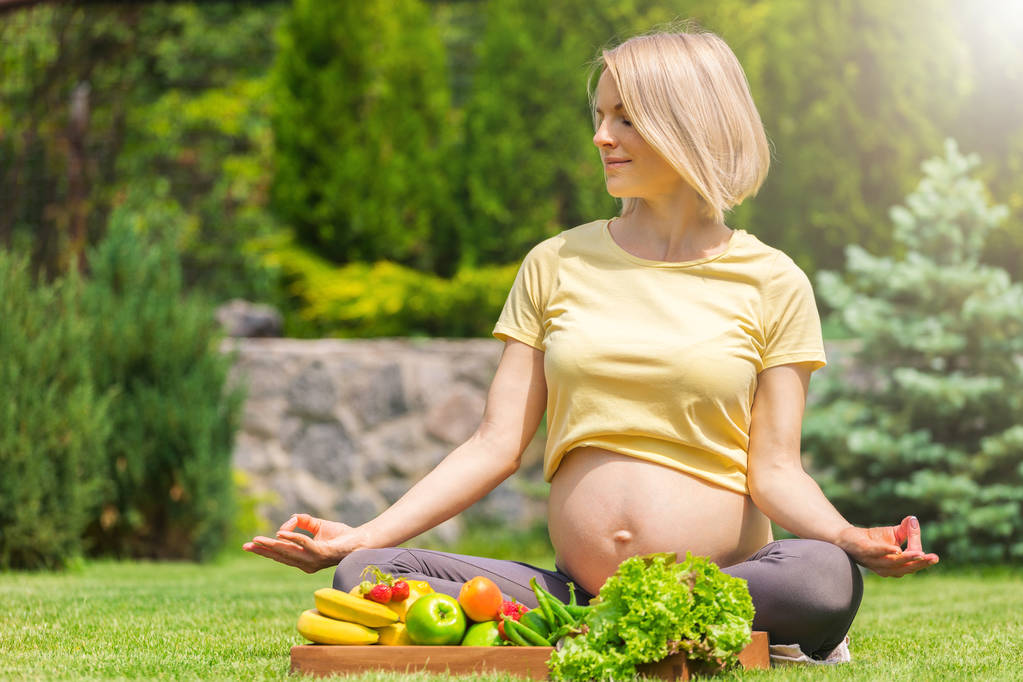 Femme enceinte pratiquant la méditation et la relaxation dans la nature
 - Photo, image