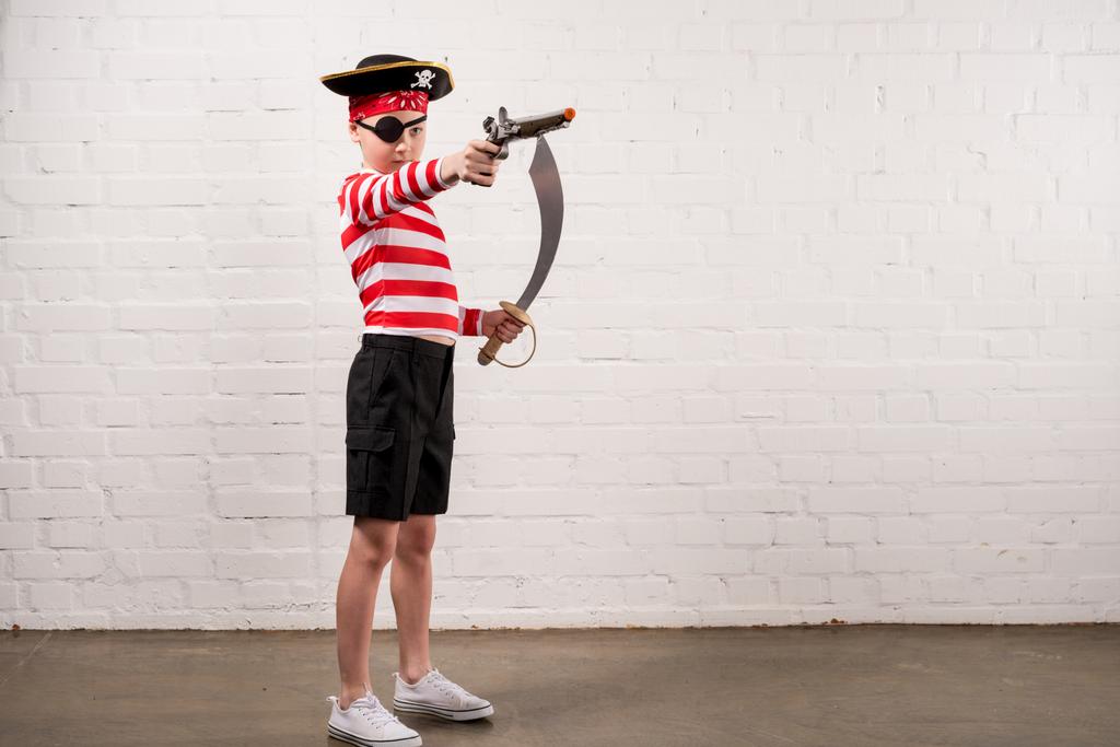 menino pré-adolescente com faca de brinquedo e arma no traje de pirata
  - Foto, Imagem