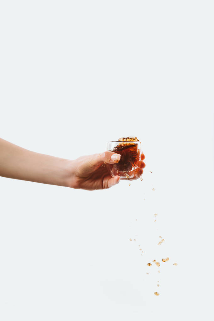 partial view of hand holding glass with splashing espresso, isolated on white - Photo, Image