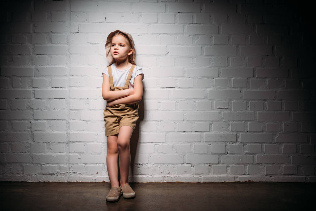 дитина в сафарі костюм з схрещеними руками, стоячи на білій стіні
 - Фото, зображення