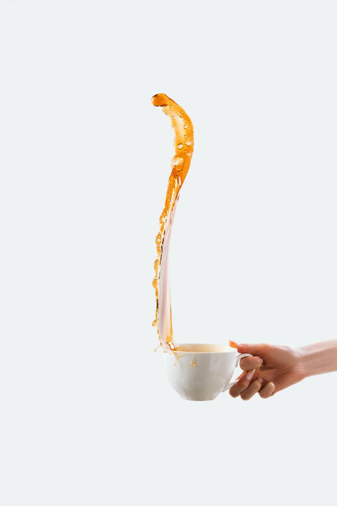 コーヒーは、白で隔離のスプラッシュと大きな白いカップを持っている手のトリミング ビュー - 写真・画像