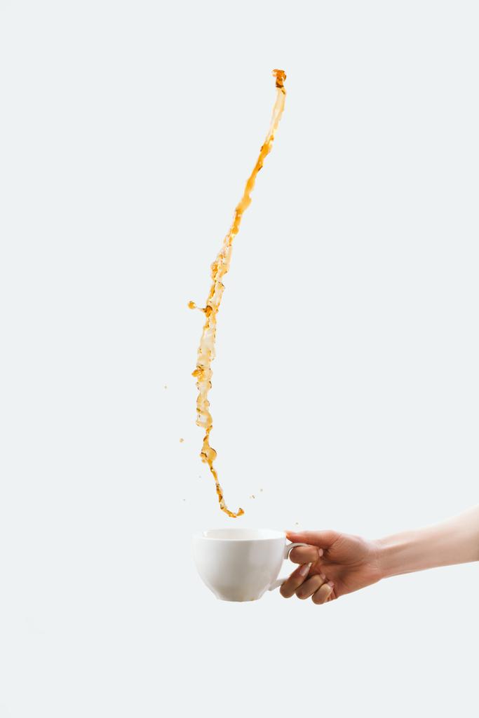 részleges kilátás nyílik a kezében a csésze forró fröccsenő kávé, elszigetelt fehér - Fotó, kép
