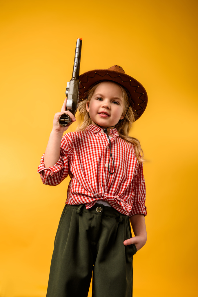 κομψό καουμπόισσα στο καπέλο με όπλο, απομονώνονται σε κίτρινο - Φωτογραφία, εικόνα