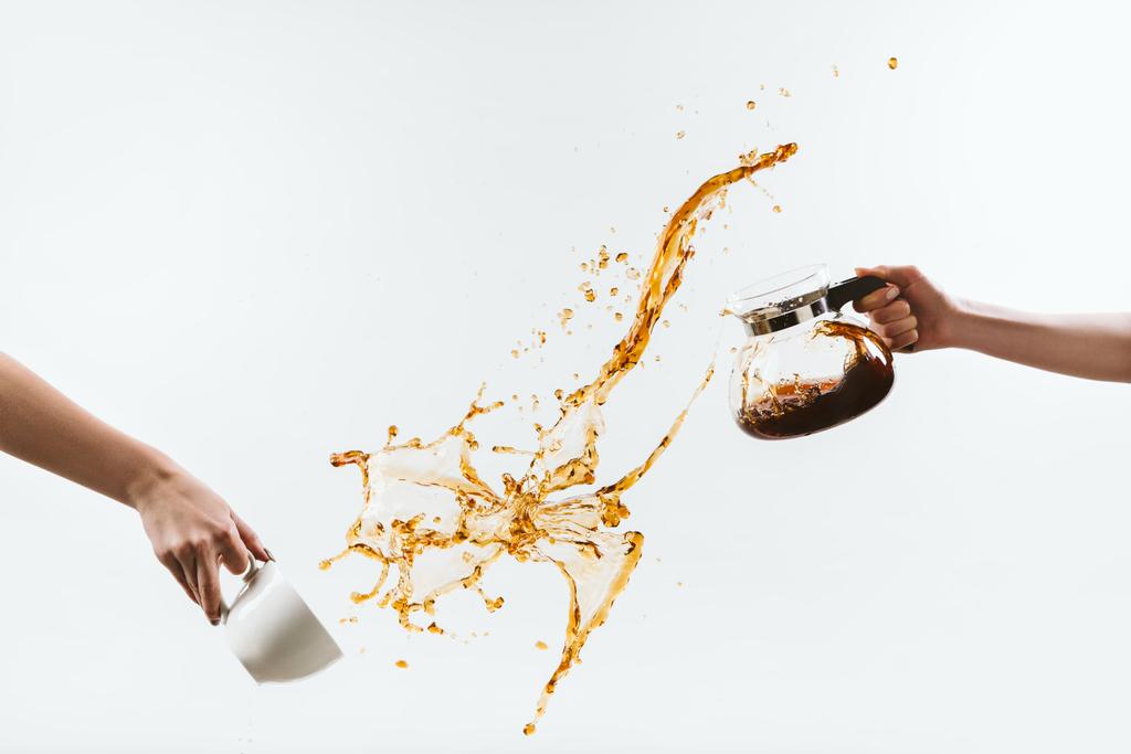 περικοπεί δείτε χέρια πιτσίλισμα ζεστό καφέ από την κατσαρόλα και το τζάμι απομονωθεί σε λευκό - Φωτογραφία, εικόνα