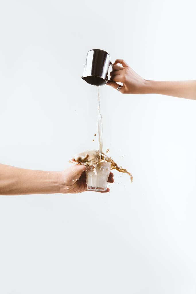 przycięte widzenia ręka rozpryskiwania mleka do szklanki kawy, na białym tle - Zdjęcie, obraz