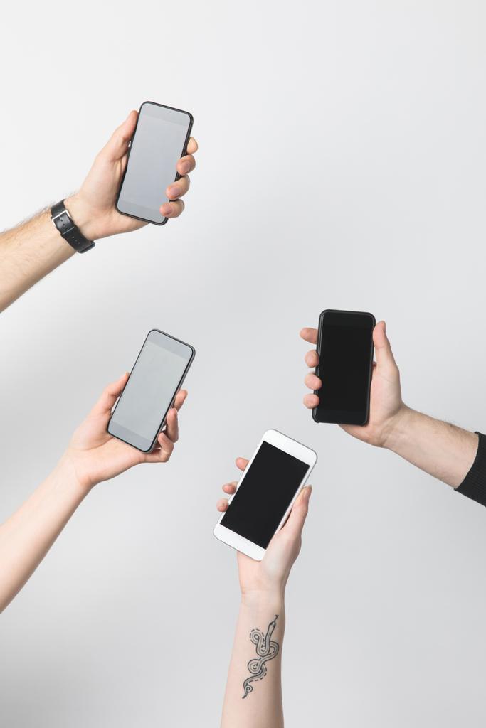 частичный просмотр группы людей со смартфонами с пустыми экранами, изолированными на белом
 - Фото, изображение