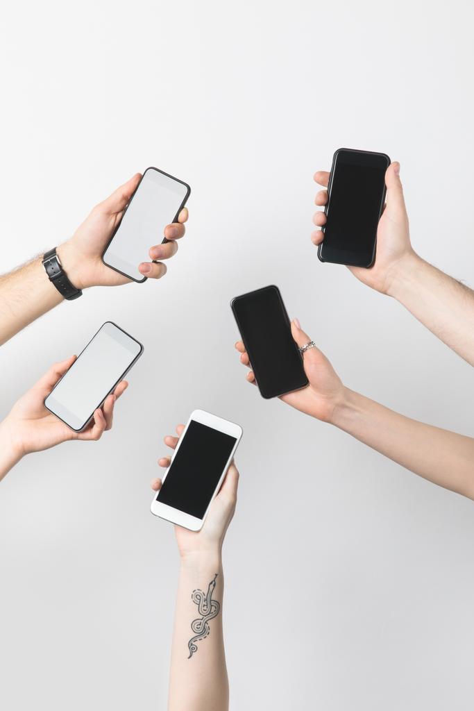 vista parcial del grupo de personas con smartphones con pantallas en blanco aisladas en blanco
 - Foto, imagen