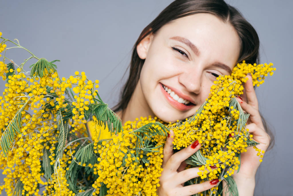 feliz joven sosteniendo un gran ramo de mimosa amarilla y riendo
 - Foto, imagen