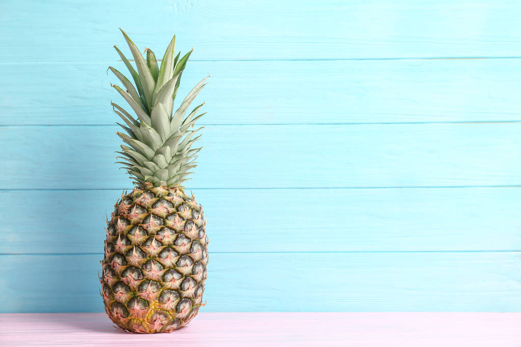 Fresh pineapple on table against color wall - Photo, Image