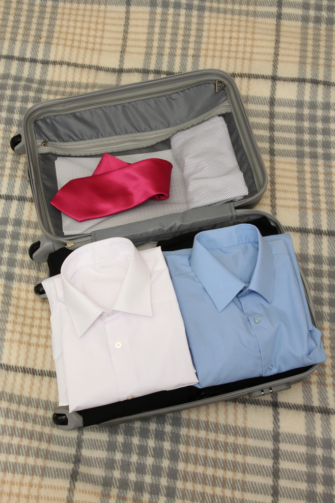 offener grauer Koffer mit Kleidung auf Karo - Foto, Bild