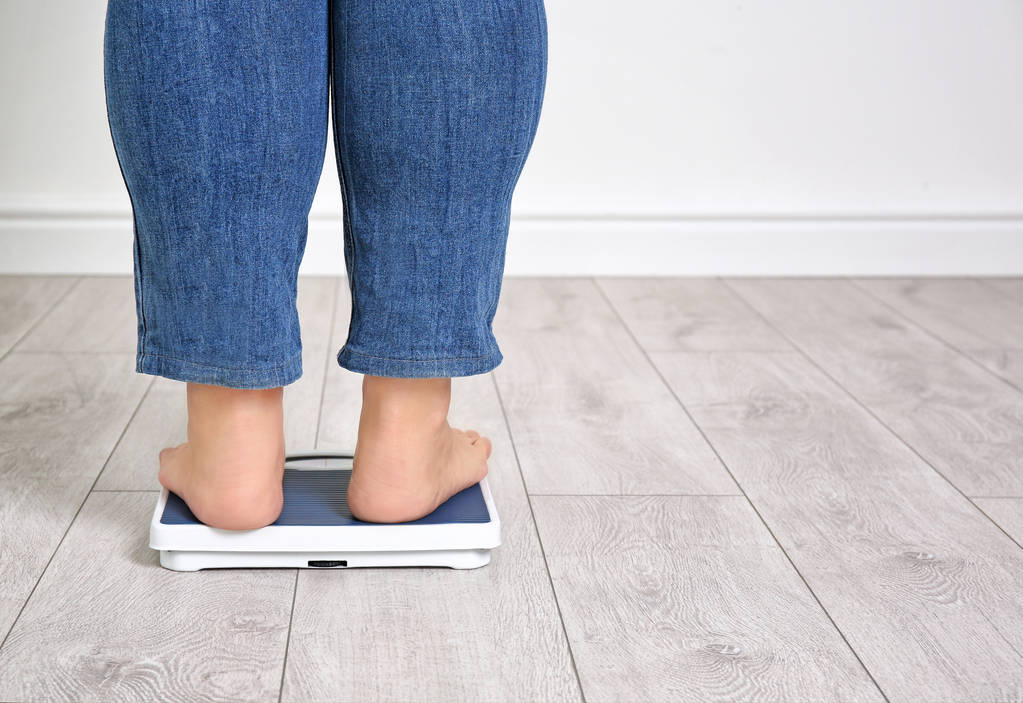 Надмірна вага жінки, використовуючи ваги в приміщенні
 - Фото, зображення