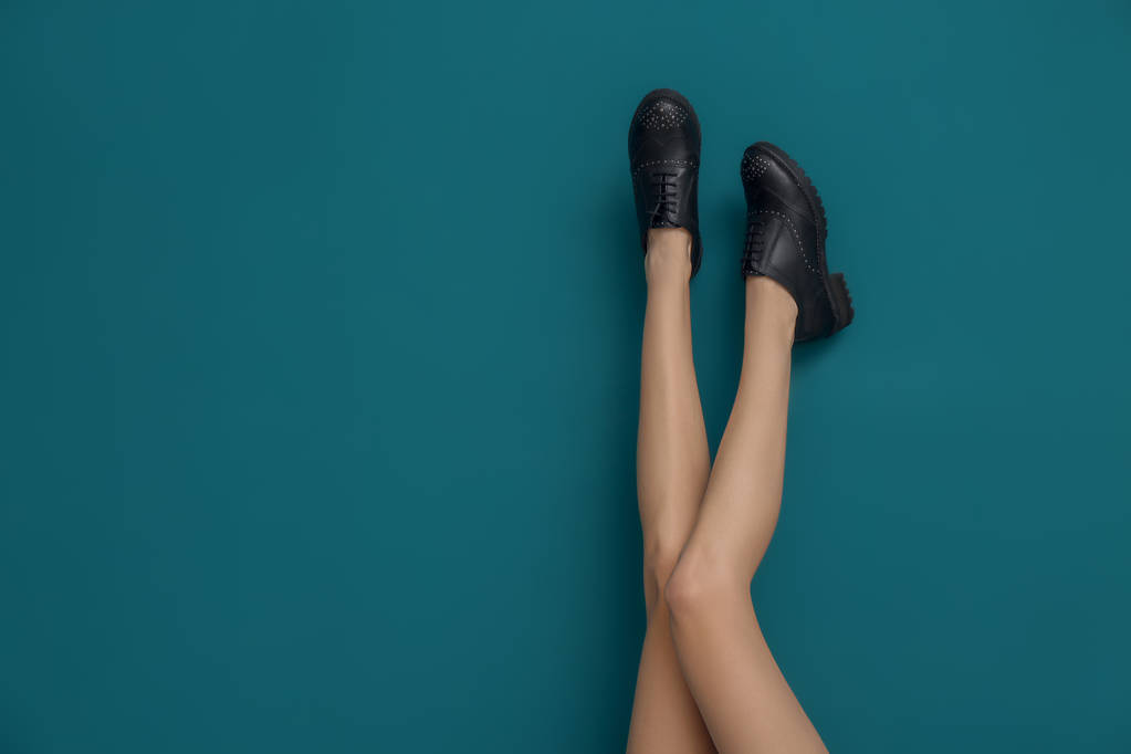 Ноги красивой женщины в стильной обуви на цветном фоне
 - Фото, изображение