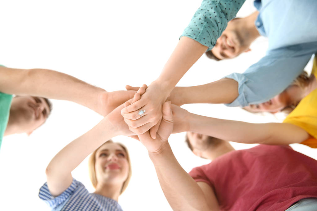 Young people putting hands together on light background. Unity concept - Photo, Image