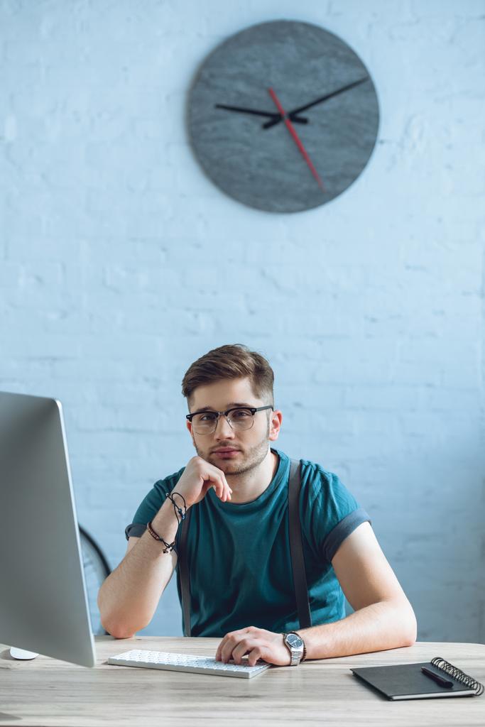 pohledný mladý freelancer v brýlí pomocí stolního počítače v domácí kanceláři - Fotografie, Obrázek
