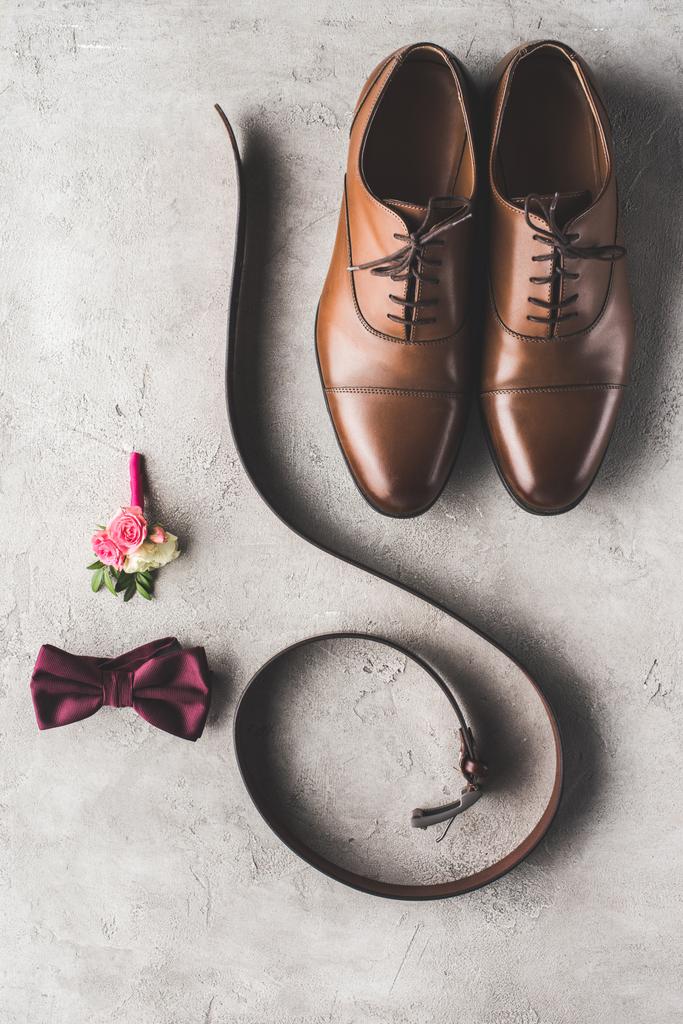 vista superior de sapatos de casamento, gravata borboleta, boutonniere e cinto na superfície cinza
 - Foto, Imagem