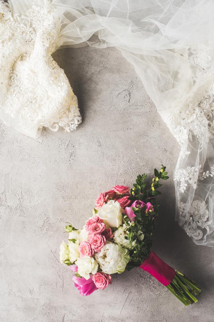 vista superior del vestido de novia y ramo de flores en la superficie gris
 - Foto, imagen