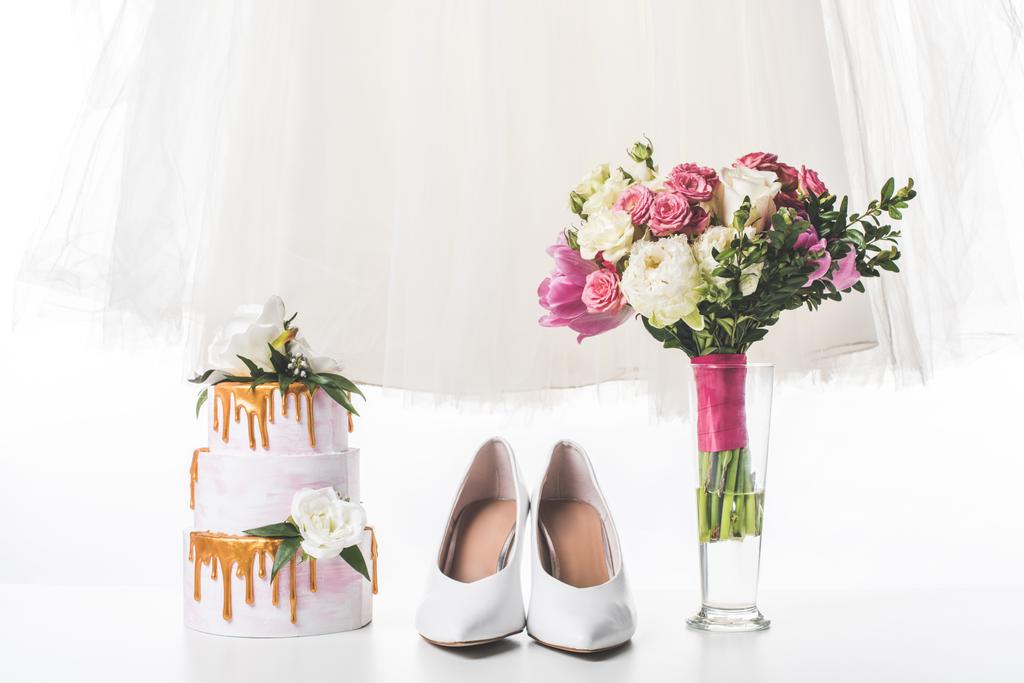 Hochzeitstorte mit Schuhen, Kleid und Strauß isoliert auf weiß - Foto, Bild
