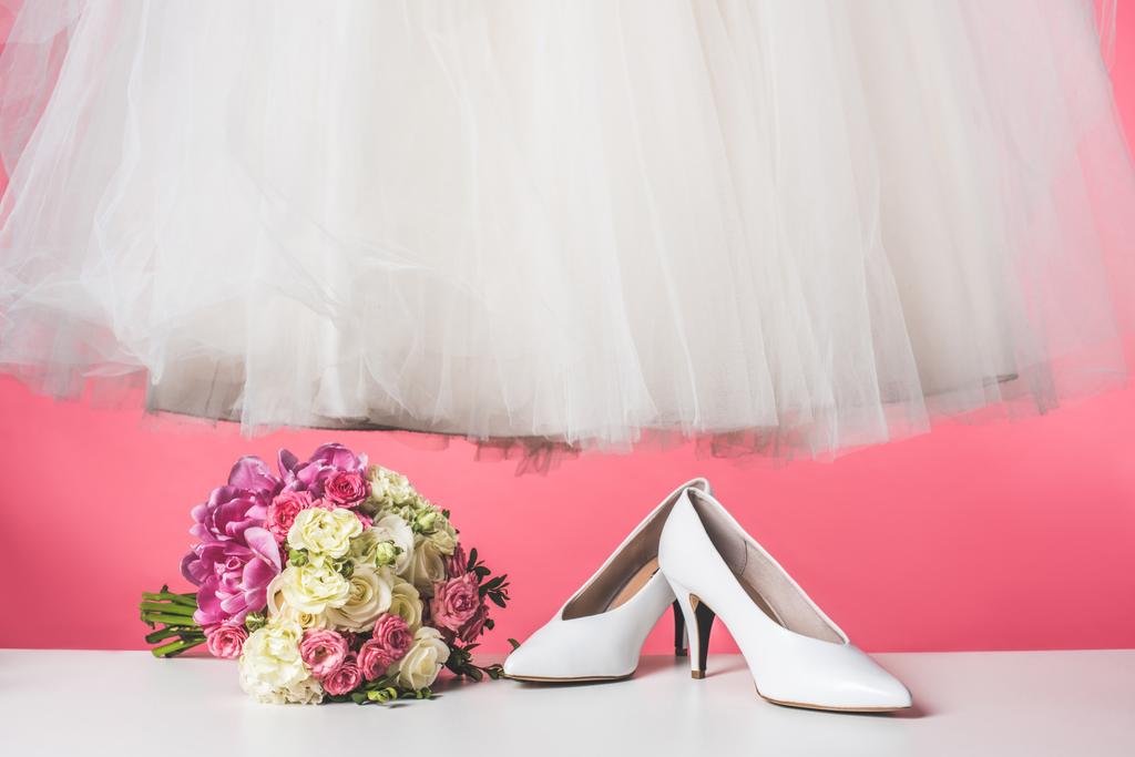 pair of shoes, wedding bouquet and white dress isolated on pink - Photo, Image