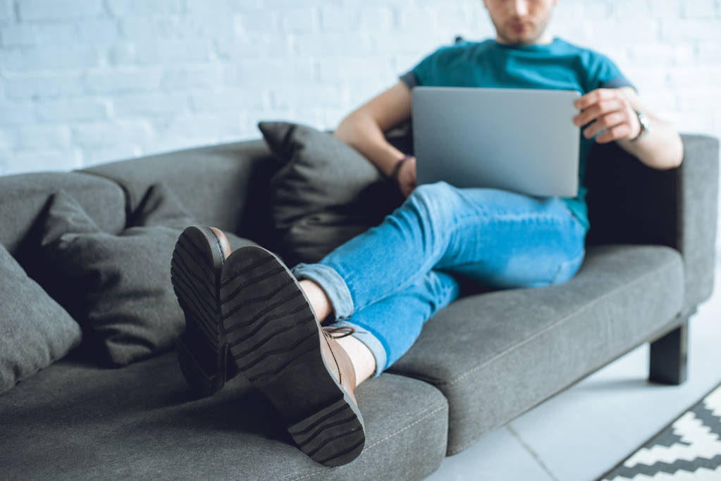 Schnappschuss eines jungen Mannes mit Laptop auf dem heimischen Sofa - Foto, Bild