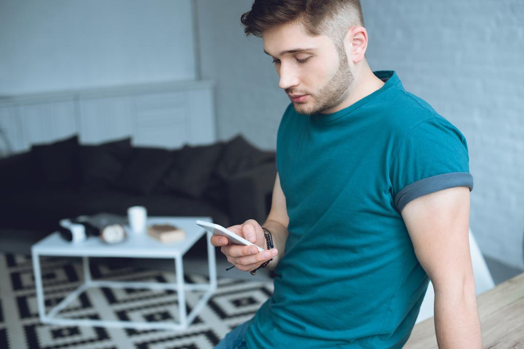 schöner junger Mann mit Smartphone zu Hause - Foto, Bild