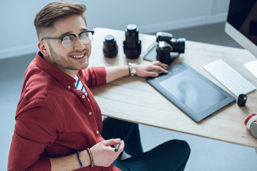 Щасливий фрілансер чоловік сидить за робочим столом з графічним планшетом
 - Фото, зображення