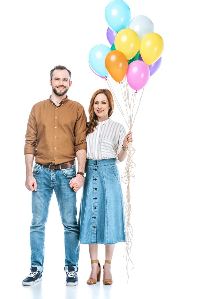 szczęśliwa para z kolorowych balonów, trzymając się za ręce i uśmiecha się do kamery na białym tle - Zdjęcie, obraz