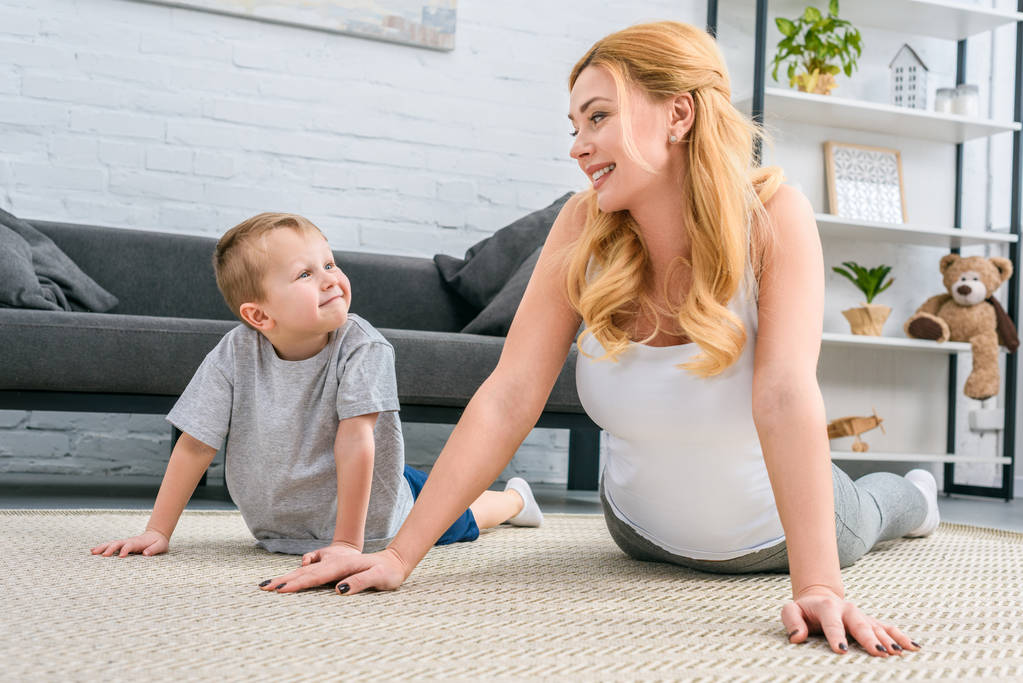 Boldog anya és fia gyakorló jóga a modern nappali  - Fotó, kép