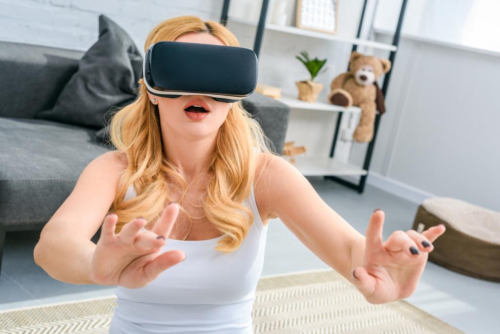 Giovane donna scioccata utilizzando auricolare realtà virtuale
   - Foto, immagini