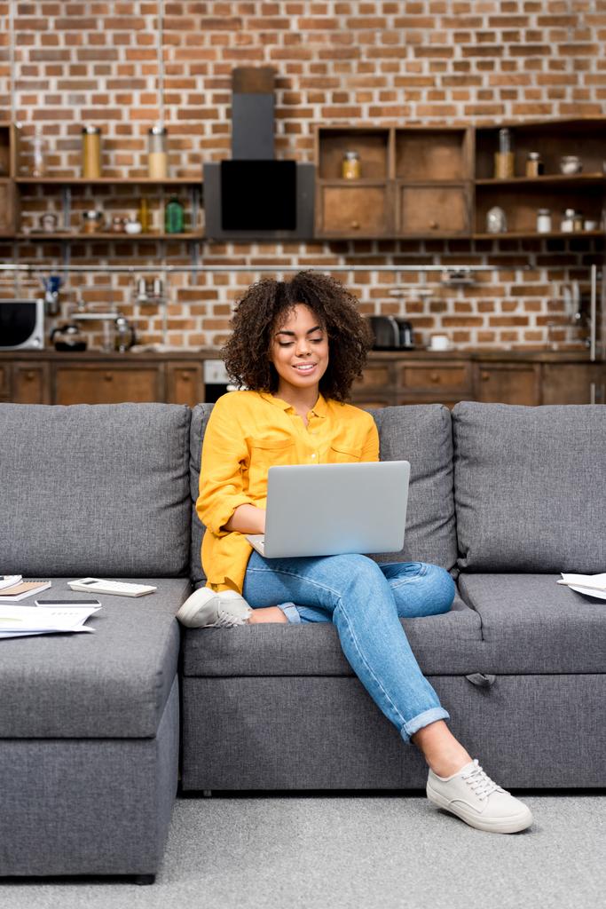 beautiful mixed race woman working working with laptop on couch - Photo, Image