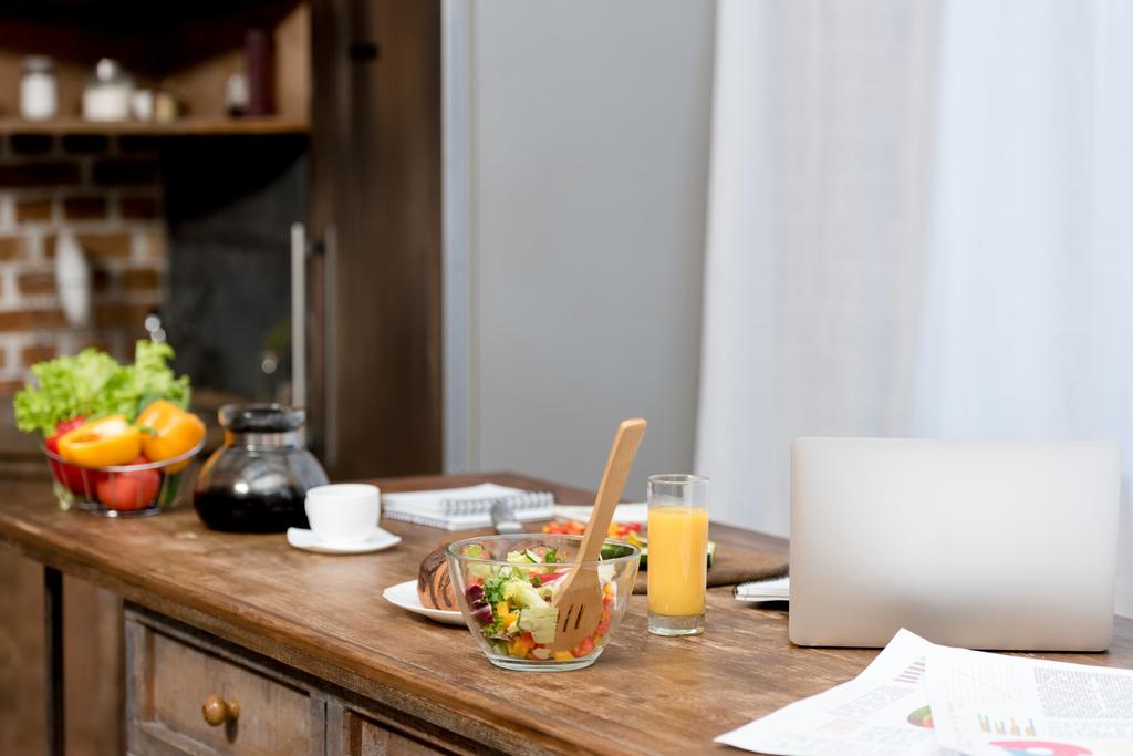 close-up de local de trabalho freelancer na cozinha com comida na mesa e laptop
 - Foto, Imagem