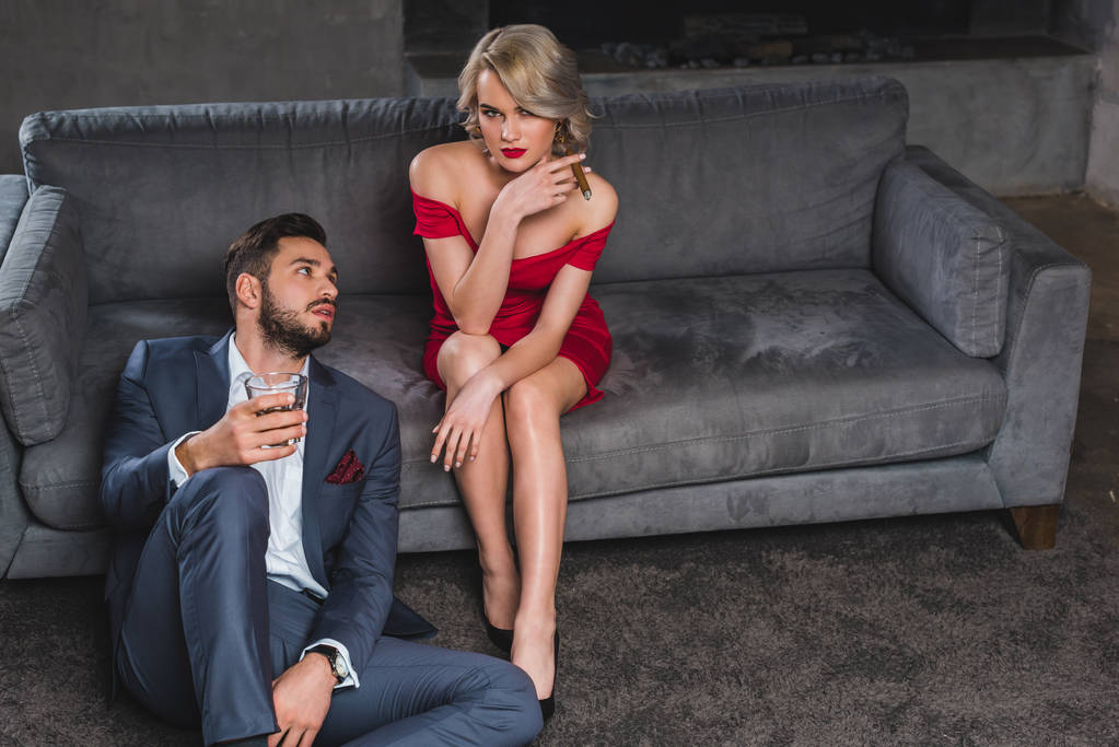 hombre guapo en traje sosteniendo vaso de whisky y mirando sexy chica con cigarro
 - Foto, imagen