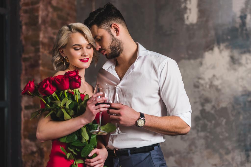 séduisant jeune couple buvant du vin rouge, femme tenant de belles roses
 - Photo, image