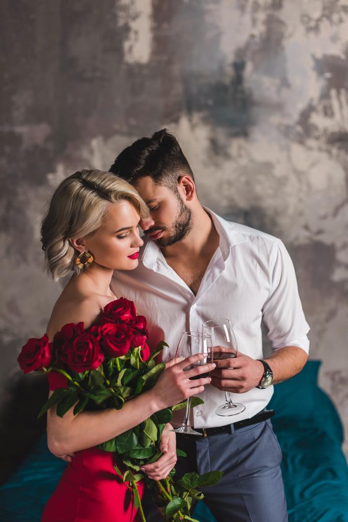 seductora joven sosteniendo hermosas rosas y bebiendo vino con novio guapo
  - Foto, imagen